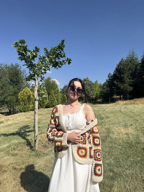 Customer in a field wearing a cream cardigan with a crochet bag