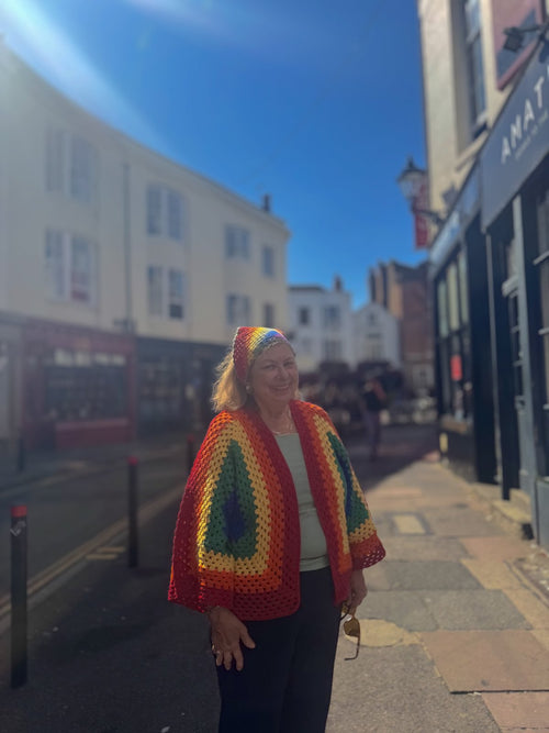 Customer in a rainbow crochet poncho at golden hour