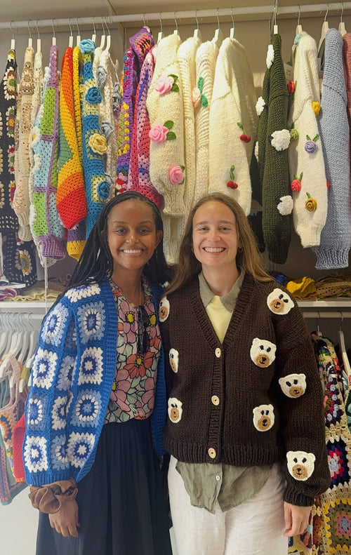 Two customers in granny-square cardigans inside the shop