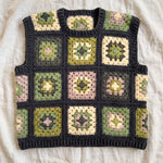Green granny square crochet vest, front, laid flat on linen