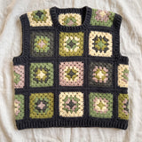 Green granny square crochet vest, front, laid flat on linen