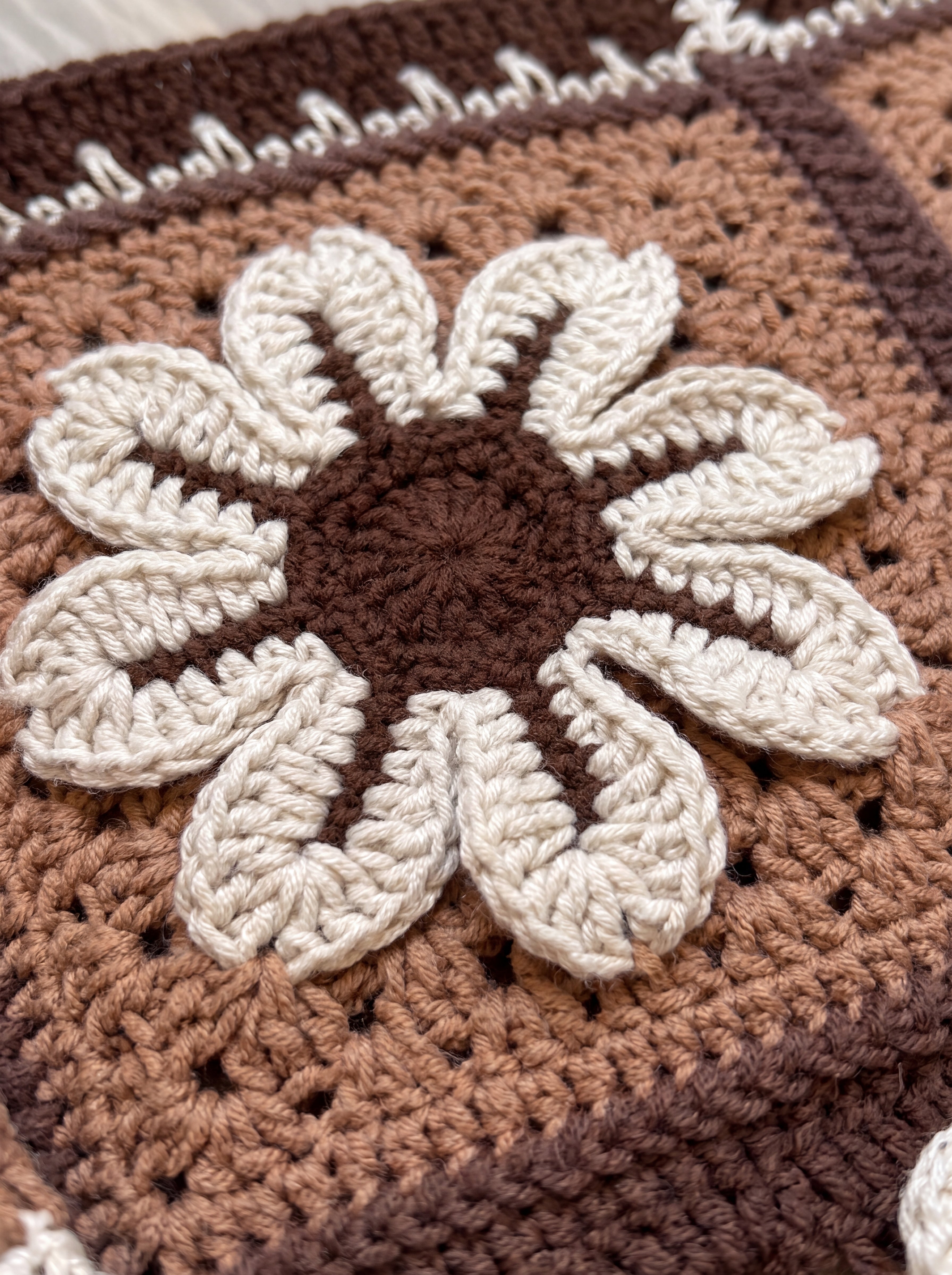 Macro of a raised hand-crocheted flower square on the Sampler Cardigan in Brown