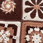 Close-up of four different hand-crocheted squares on the Sampler Cardigan in Brown, each a different motif design