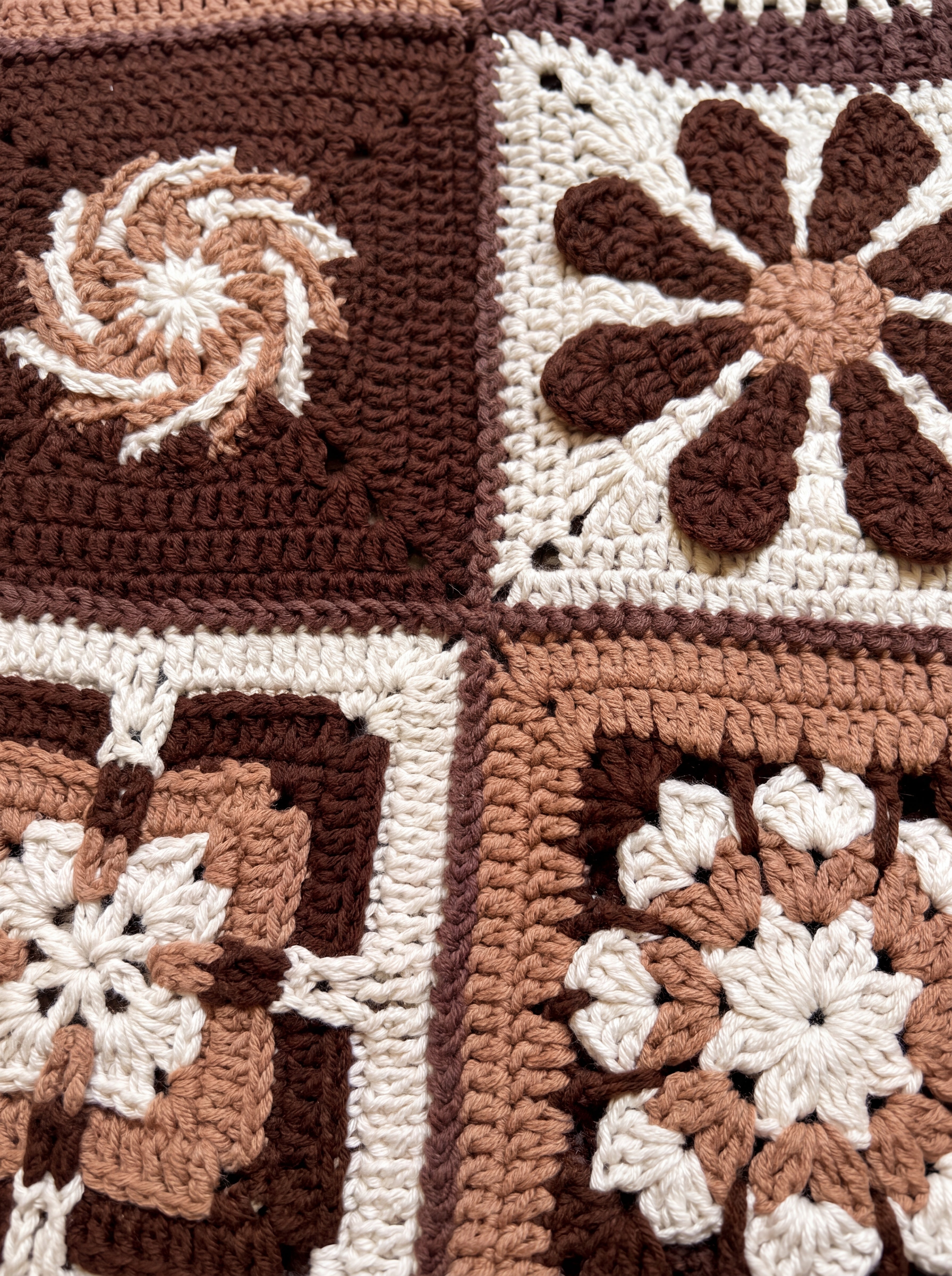 Close-up of four different hand-crocheted squares on the Sampler Cardigan in Brown, each a different motif design