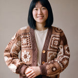 Woman wearing the Sampler Cardigan in Brown, a hand-crocheted granny-square cardigan, over a plain t-shirt and jeans