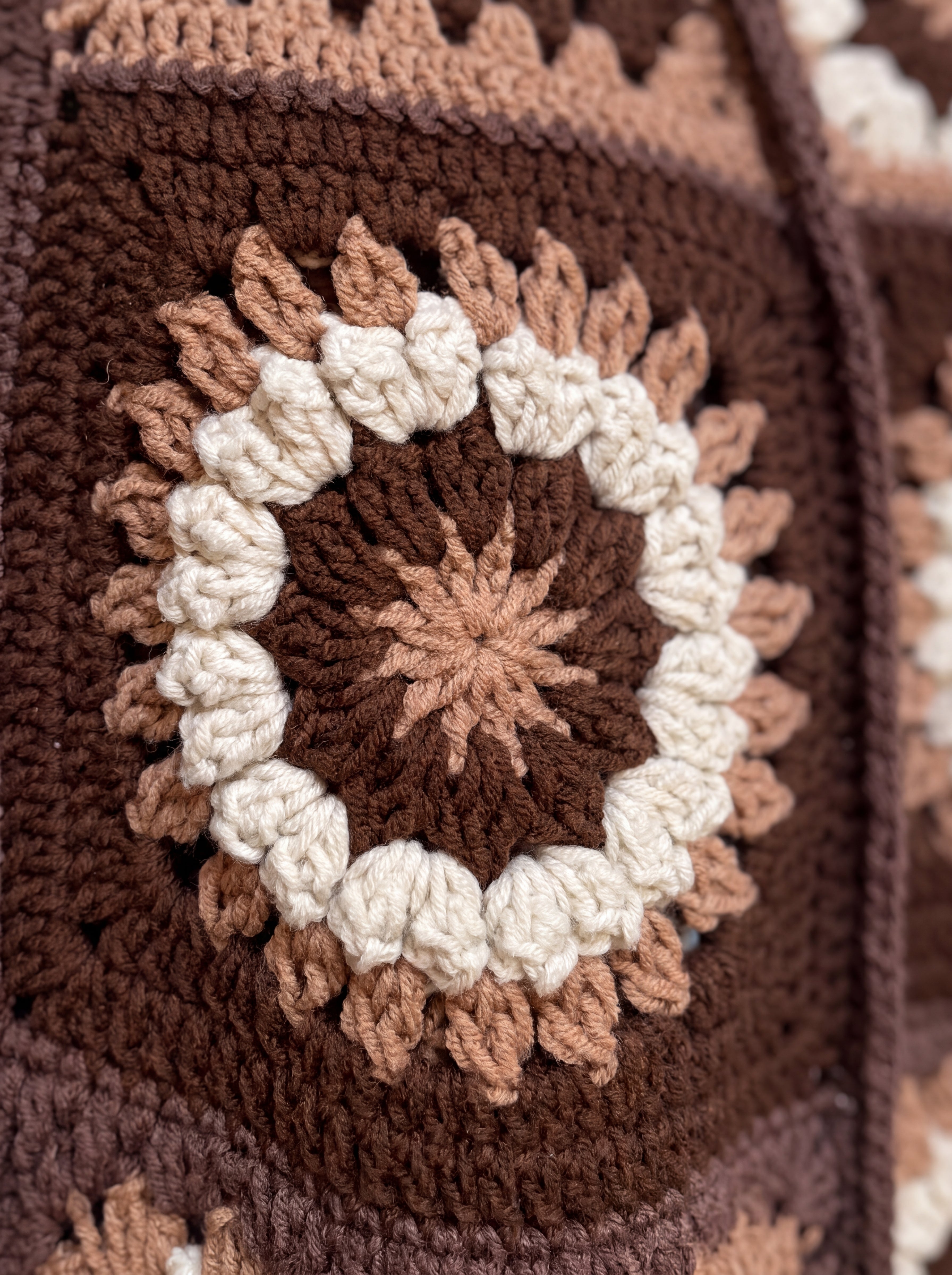 Macro of a hand-crocheted square with a ring of popcorn bobbles on the Sampler Cardigan in Brown