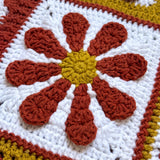 Macro of a hand-crocheted daisy square on the Sampler Cardigan in Rust
