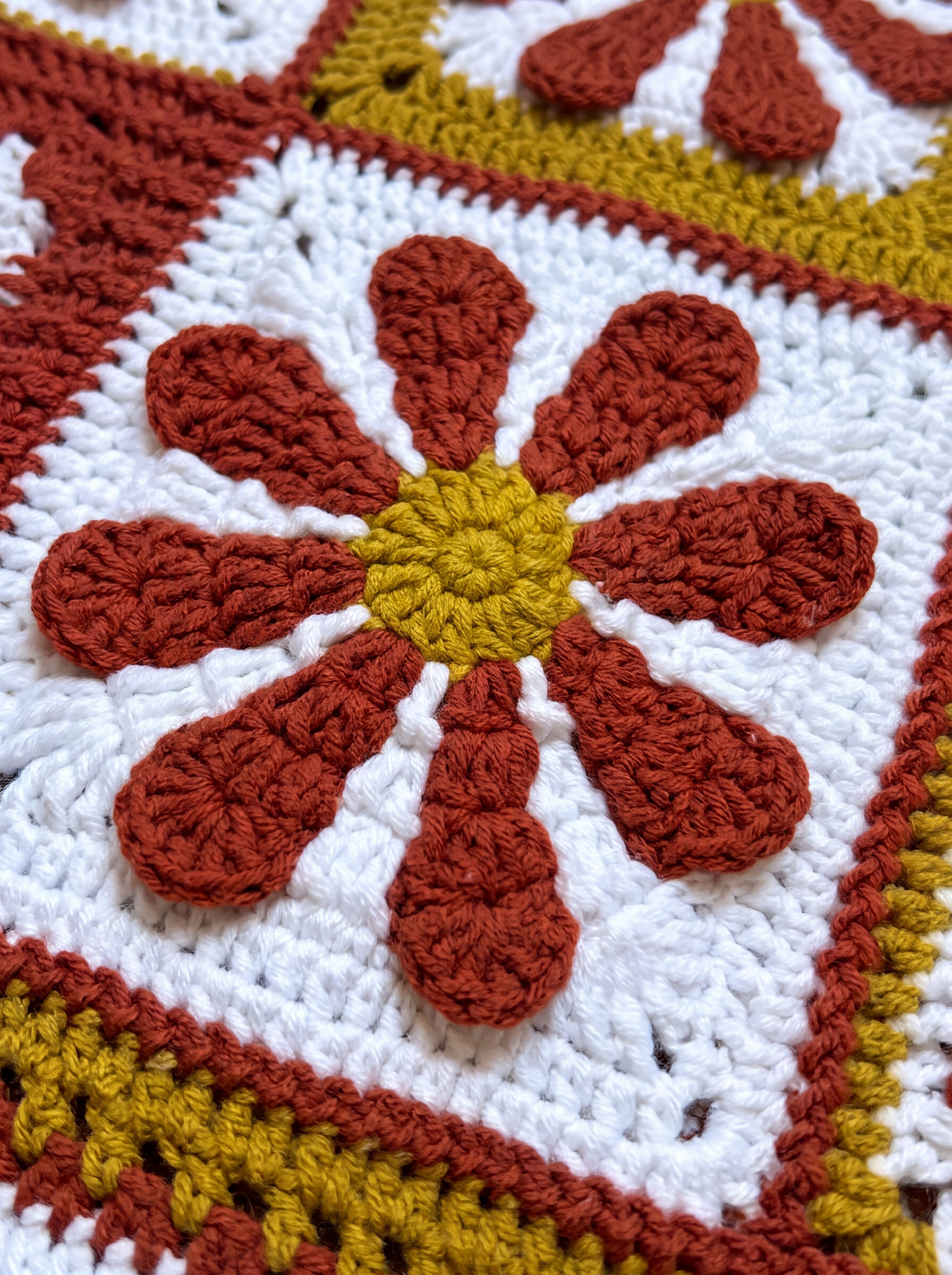 Macro of a hand-crocheted daisy square on the Sampler Cardigan in Rust