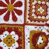 Close-up of four different hand-crocheted squares on the Sampler Cardigan in Rust, each a different motif design