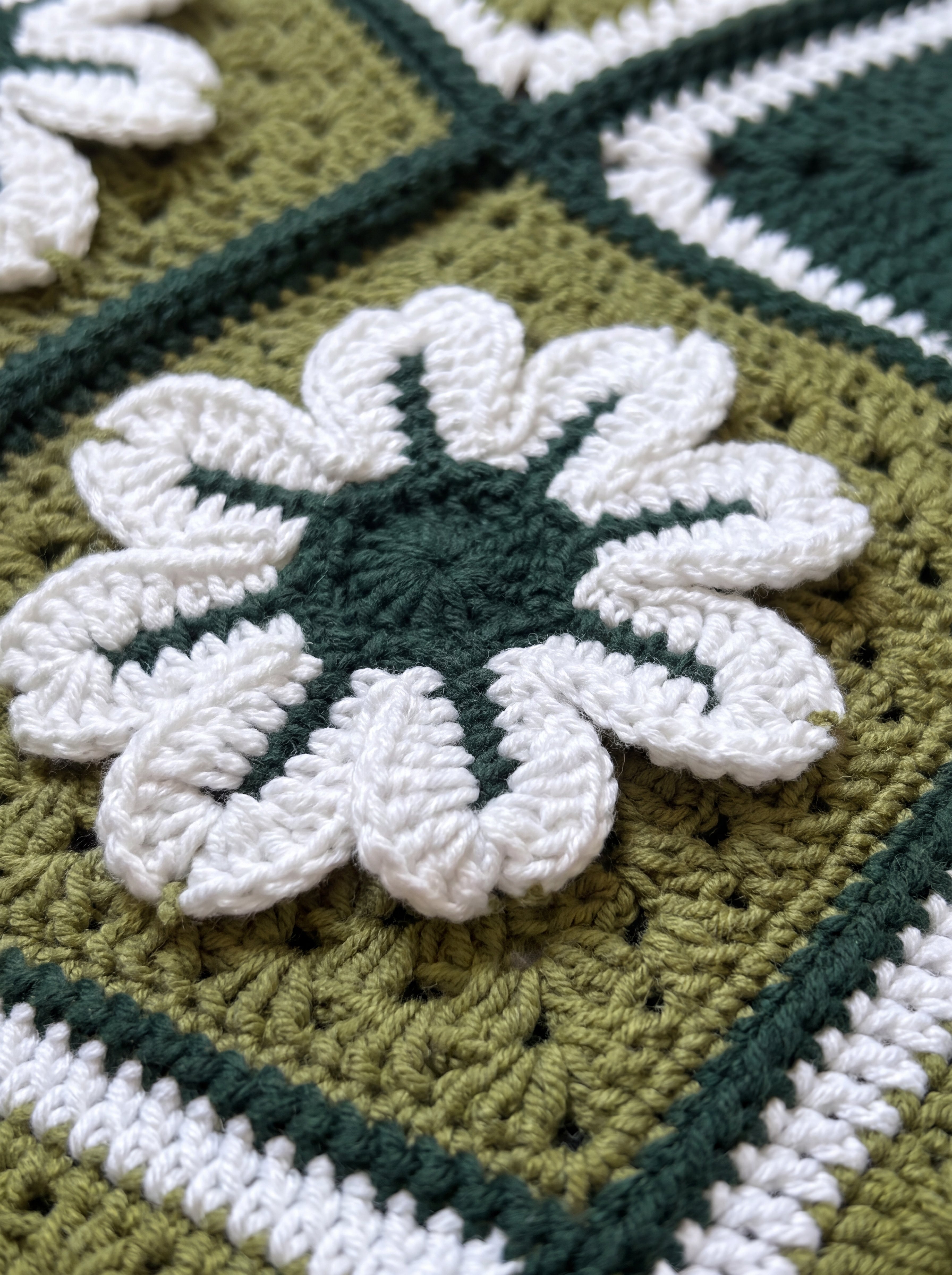 Macro of a raised hand-crocheted flower square on the Sampler Cardigan in Forest Green