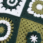 Close-up of four different hand-crocheted squares on the Sampler Cardigan in Forest Green, each a different motif design