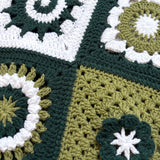 Close-up of four different hand-crocheted squares on the Sampler Cardigan in Forest Green, each a different motif design