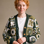 Woman wearing the Sampler Cardigan in Forest Green, a hand-crocheted granny-square cardigan, over a plain t-shirt and jeans