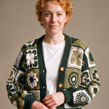 Woman wearing the Sampler Cardigan in Forest Green, a hand-crocheted granny-square cardigan, over a plain t-shirt and jeans