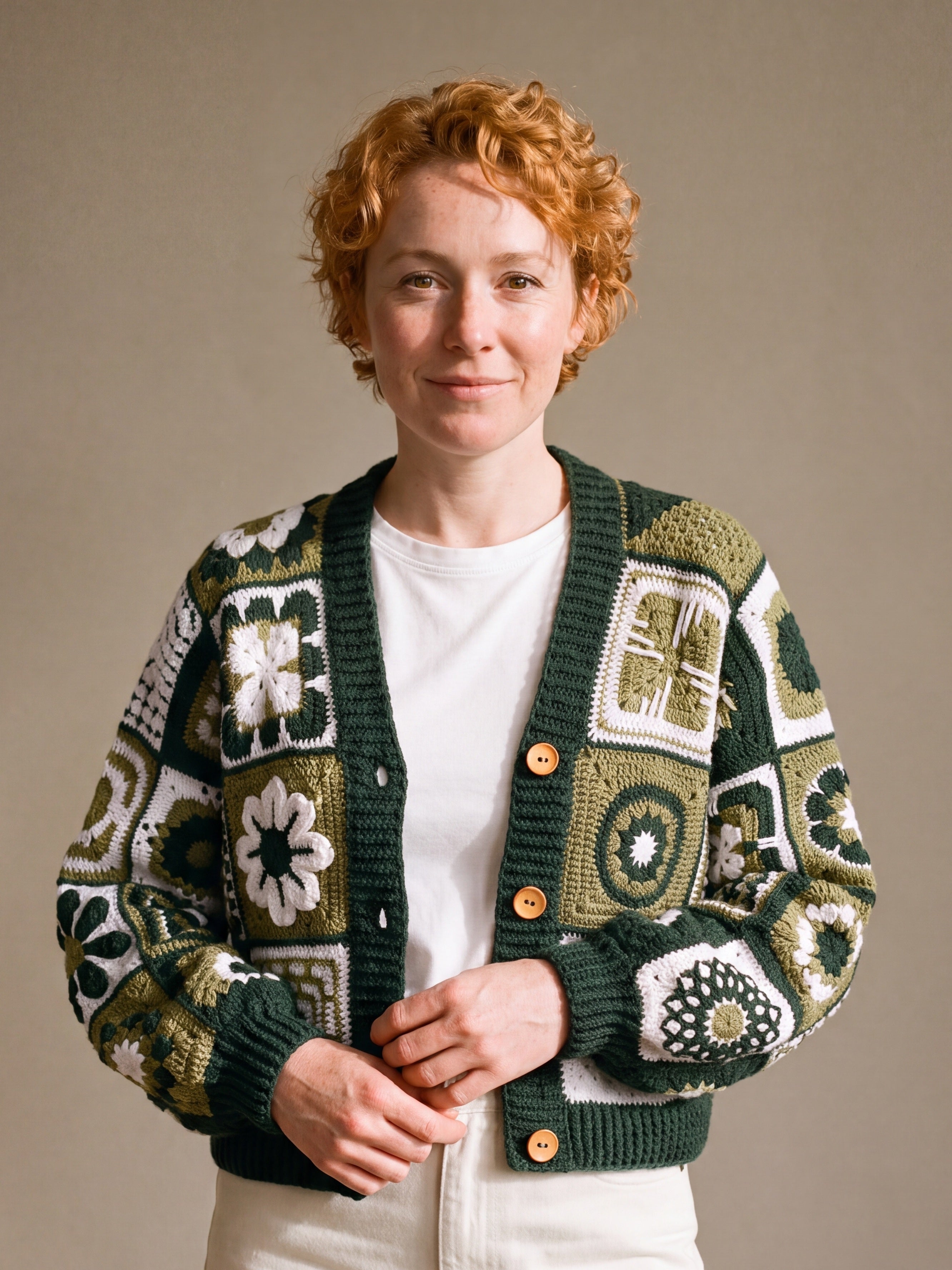 Woman wearing the Sampler Cardigan in Forest Green, a hand-crocheted granny-square cardigan, over a plain t-shirt and jeans