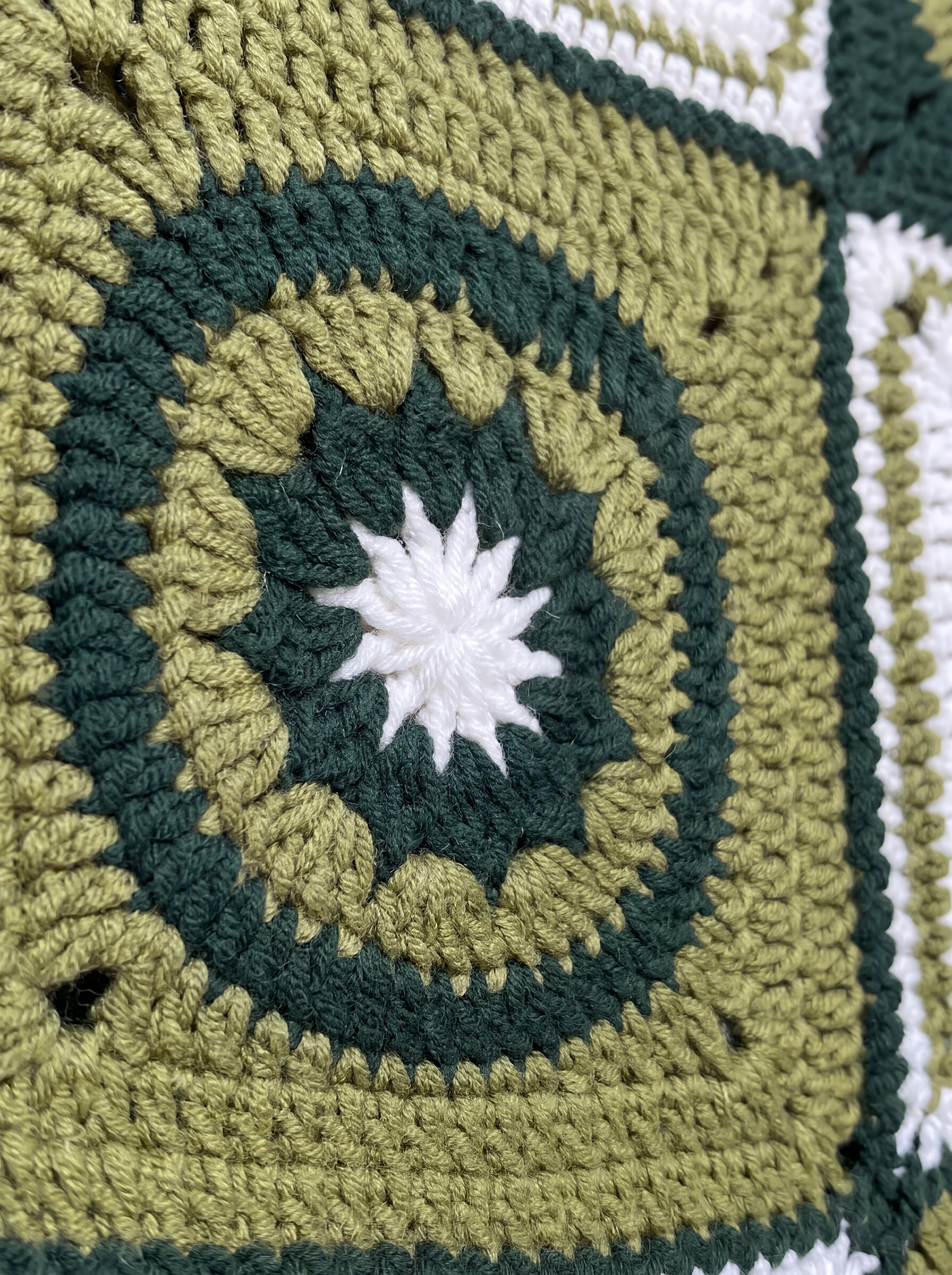 Macro of a hand-crocheted concentric star square on the Sampler Cardigan in Forest Green