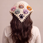 Back view of the large crochet bandana worn over long dark hair, five cat faces and a black paw on cream granny squares — handmade by Ana Chic