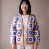 Patchwork cardigan in blue and cream granny squares with camel-beige bands, worn open over a white top - handmade by Ana Chic