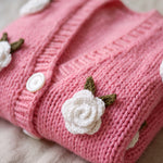 Detail of the Rose Bubblegum cardigan — a crocheted white rose with green leaves and a white button on bubblegum pink chunky hand-knitted wool, handmade by Ana Chic