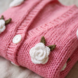 Detail of the Rose Bubblegum cardigan — a crocheted white rose with green leaves and a white button on bubblegum pink chunky hand-knitted wool, handmade by Ana Chic