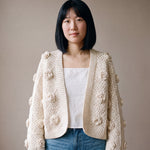 Woman wearing the ecru crochet rose cardigan open over a white camisole and blue jeans — handmade by Ana Chic