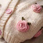 Detail of the Rose Cream cardigan — a crocheted pink rose with green leaves and a pink button on cream chunky hand-knitted wool, handmade by Ana Chic