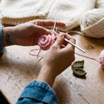 Hands crocheting a pink rose for the Rose Cream cardigan in the atelier — handmade by Ana Chic