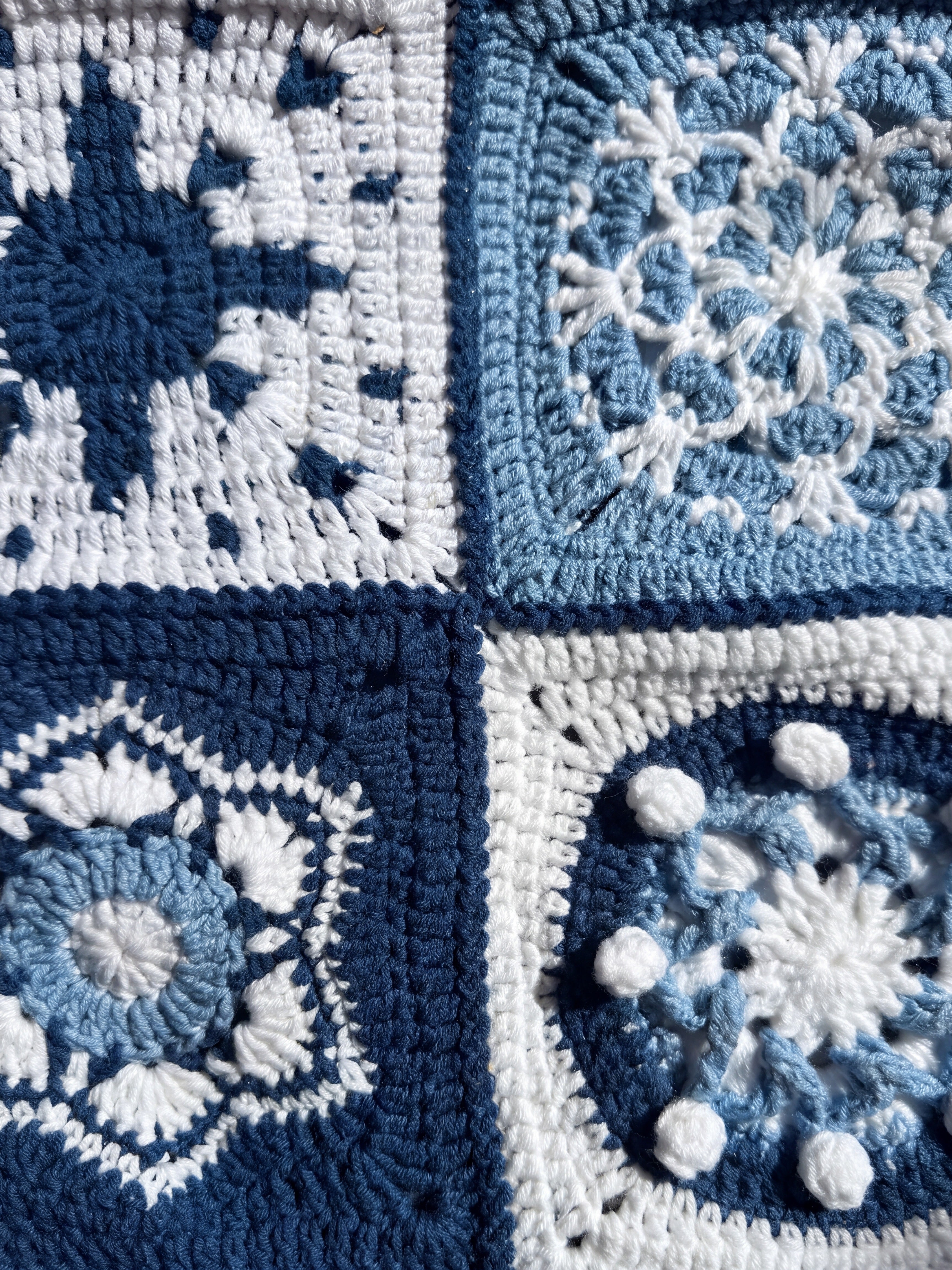 Close-up of four different hand-crocheted squares on the Sampler Long Cardigan: compass star, snowflake, shell hexagon and popcorn disc