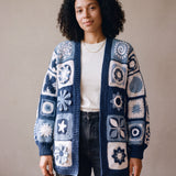 Woman wearing the Sampler Long Cardigan open over a white t-shirt and black jeans, hand-crocheted granny squares in navy, blue and white