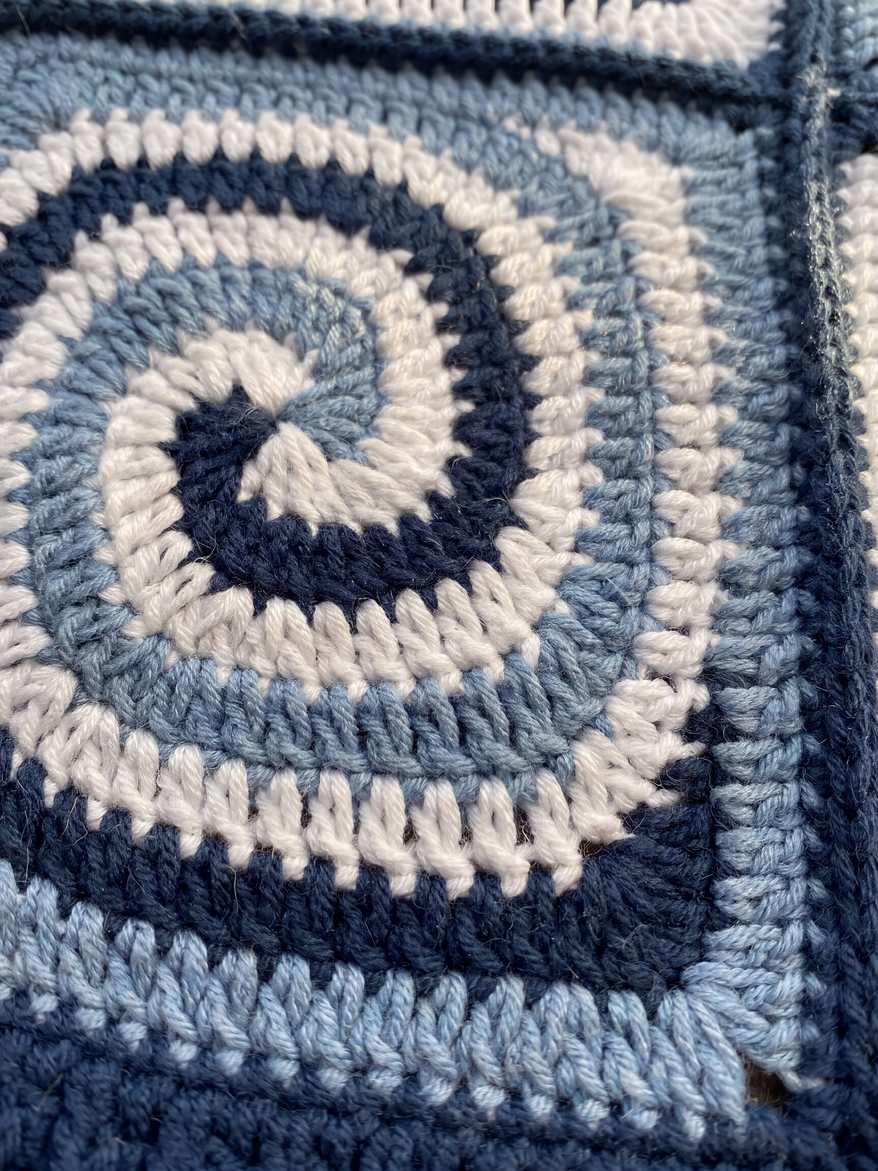 Macro of a hand-crocheted spiral square in navy, powder blue and white, Sampler Long Cardigan