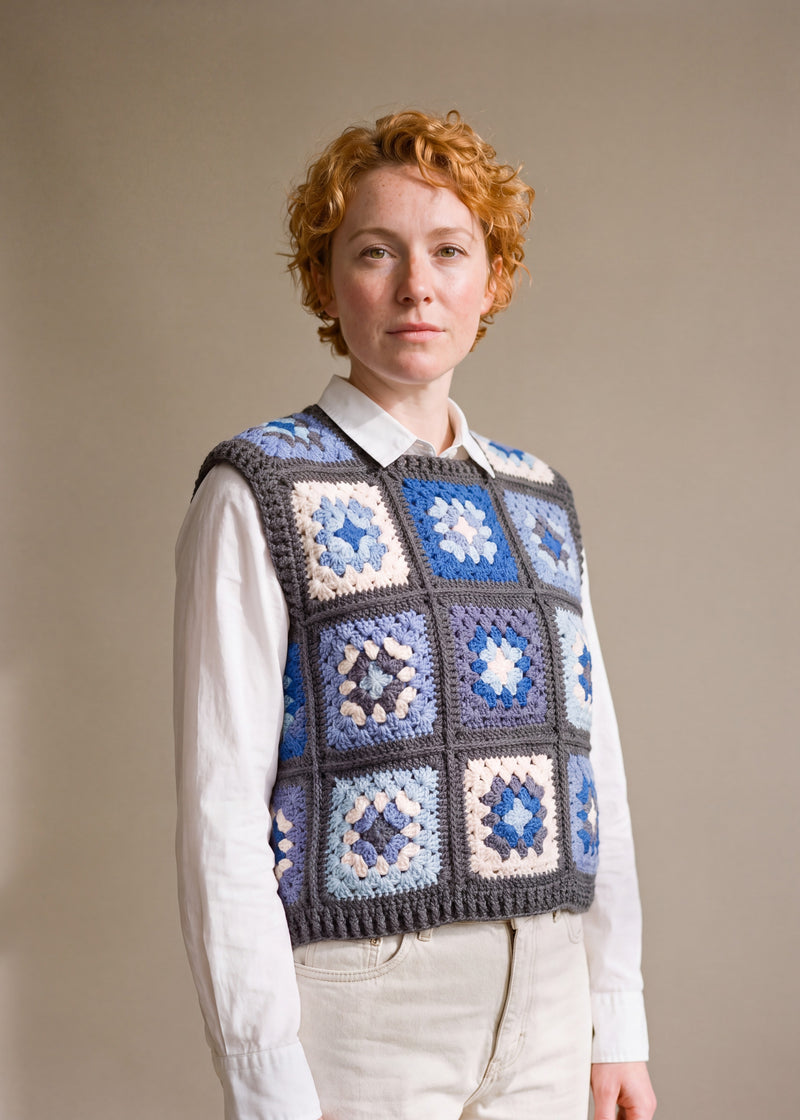 Blue granny square crochet vest worn over a white shirt