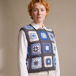 Blue granny square crochet vest worn over a white shirt