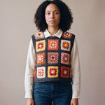 Terracotta granny square crochet vest worn over an ecru linen shirt