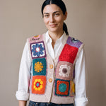 Woman wearing the Lanes Spirit Vest, a handmade granny square crochet vest, over a white shirt and dark jeans