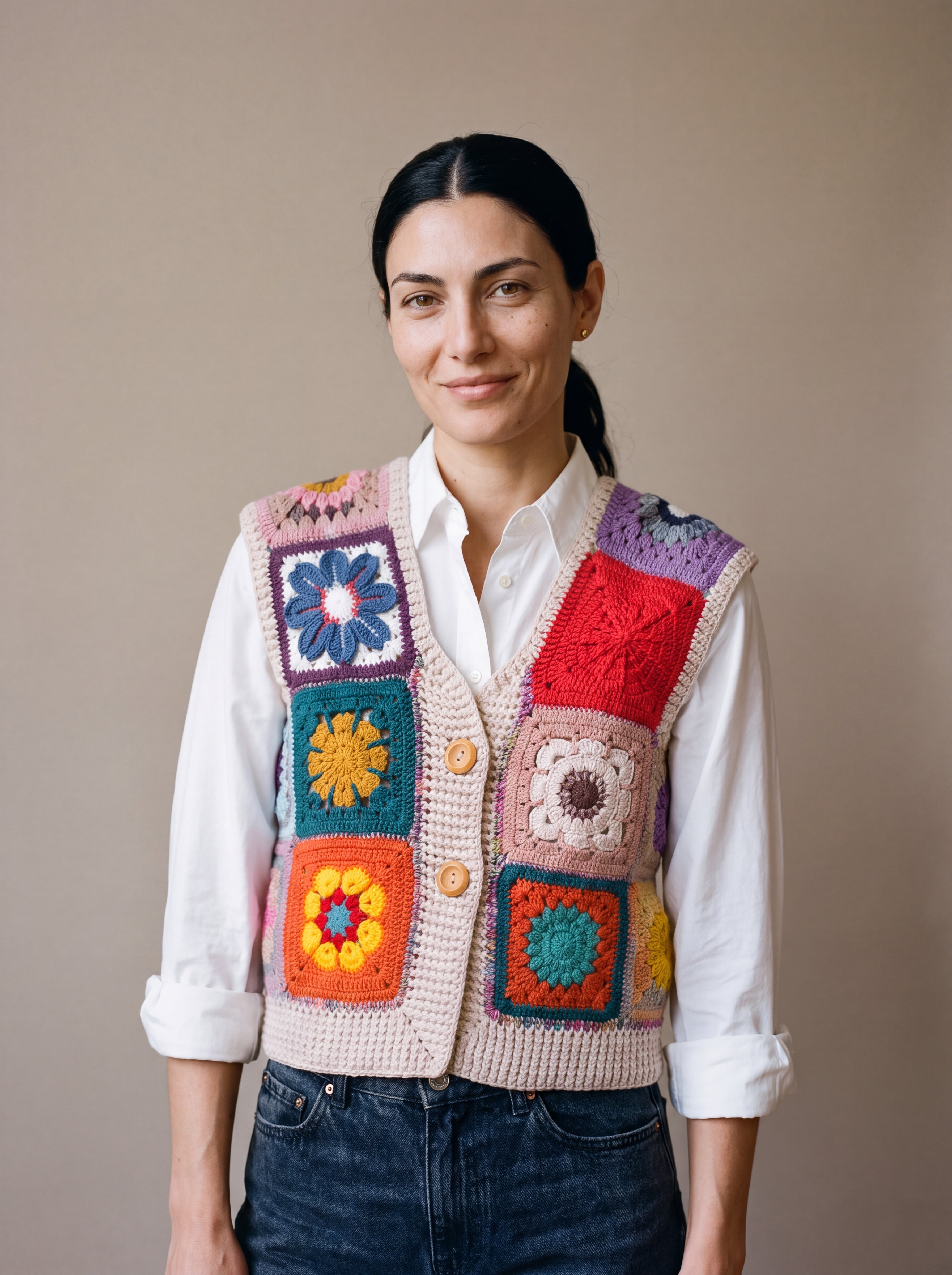 Woman wearing the Lanes Spirit Vest, a handmade granny square crochet vest, over a white shirt and dark jeans