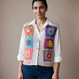 Woman wearing the Confetti Vest, a handmade granny square crochet vest, over a white shirt and dark jeans