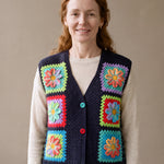 Woman wearing the Moonflower Vest, a handmade granny square crochet vest, over an ecru knit top and blue jeans